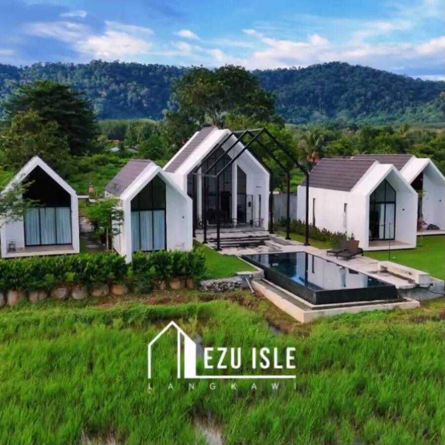Ezu Isle: white A-frame villas and infinity pool set in green padi fields, rainforest hills behind